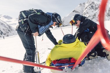 Pistenrettung im Einsatz in Gargellen | © Gargellner Bergbahnen GmbH & Co KG, Daniel Zangerl Zwei Mitglieder der Pistenrettung sichern einen verletzten Skifahrer auf dem Akia, um ihn sicher ins Tal zu bringen. Mit Präzision und Erfahrung arbeiten sie Hand in Hand auf der verschneiten Piste in Gargellen. | © Gargellner Bergbahnen GmbH & Co KG, Daniel Zangerl