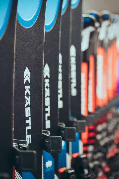Aktuelles Material in den beiden Skiverleihen PME Shop & Rent und Täli Sport - Mode Rent | © Gargellner Bergbahnen GmbH & Co KG, Christoph Schöch Mehrere Paar Ski der Marke Kästle stehen ordentlich in einer Reihe in einem Skiverleih. Die Vorderseiten der Ski in Blau, Schwarz und Rot sind deutlich zu erkennen. Der Hintergrund des Raums ist unscharf, wodurch der Fokus auf den Ski liegt. | © Gargellner Bergbahnen GmbH & Co KG, Christoph Schöch